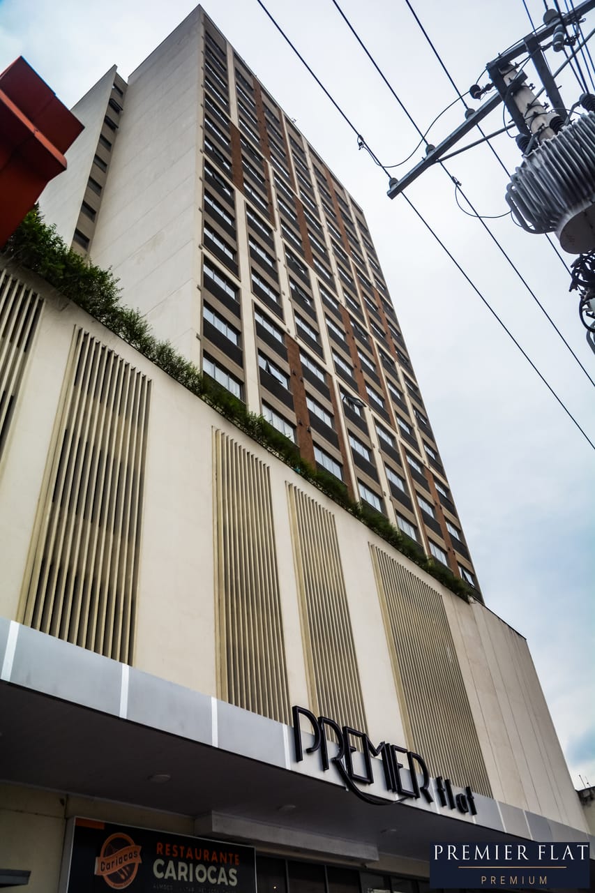 Fachada do Premier Flat Premium com letreiro na rua principal de Queimados